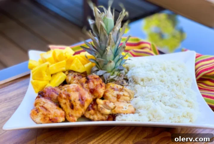 Ultimate Grilled Teriyaki Chicken 3 Two plates of grilled teriyaki chicken, coconut rice, and pineapple, ready for serving.