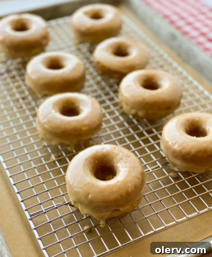 Effortless Maple Baked Donuts 7 Several maple-glazed donuts arranged beautifully on a white plate, ready to be served.