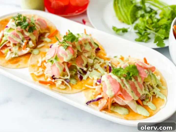 Zesty Salmon Tacos 7 Overhead shot of two salmon fish tacos on a wooden board, garnished with fresh ingredients.