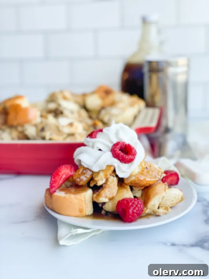 Make Ahead French Toast Bake 2 Golden brown overnight French toast casserole topped with powdered sugar and fresh berries, ready for serving.