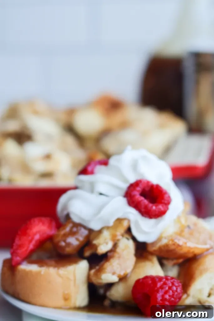 Make Ahead French Toast Bake 8 A slice of overnight French toast casserole on a white plate, drizzled with caramel sauce and garnished with a sprig of mint.