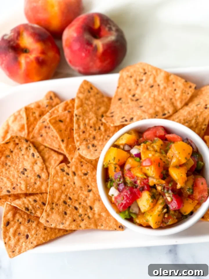 Sun-Kissed Peach Salsa 7 A full bowl of fresh peach salsa with a serving spoon, presented on a bright, inviting background, ready to be enjoyed as a summer appetizer.