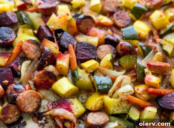 Sheet Pan Sausage and Roasted Veggies 3 Close-up of chopped chicken and apple sausage, zucchini, yellow squash, beets, carrots, and onions, all tossed with oil and Italian seasoning on a baking sheet.