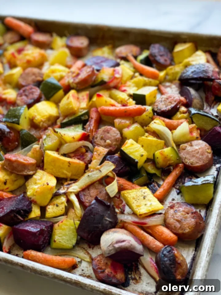 Sheet Pan Sausage and Roasted Veggies 5 A sheet pan filled with colorful roasted chicken and apple sausage and vegetables, including zucchini, yellow squash, carrots, beets, and onions, fresh out of the oven.
