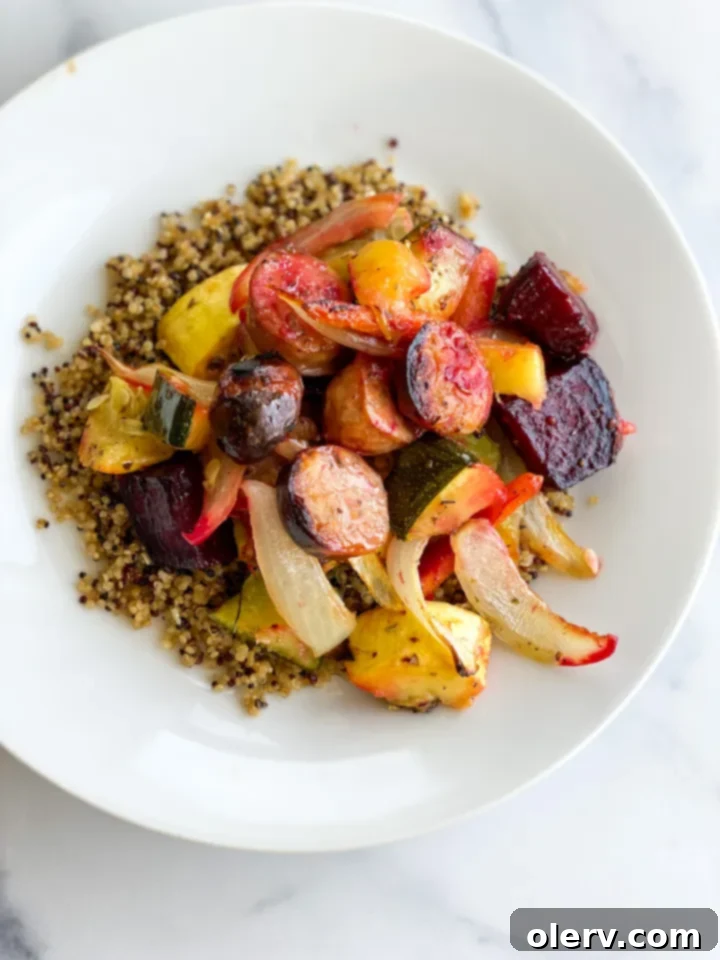 Sheet Pan Sausage and Roasted Veggies 6 A delicious serving of sheet pan chicken and apple sausage and roasted vegetables over a bed of quinoa, garnished with fresh herbs.