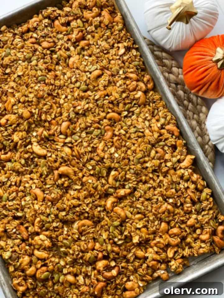 Pumpkin Spice Crunch 5 Freshly baked pumpkin granola, golden brown and clumpy, cooling on a parchment-lined baking sheet.