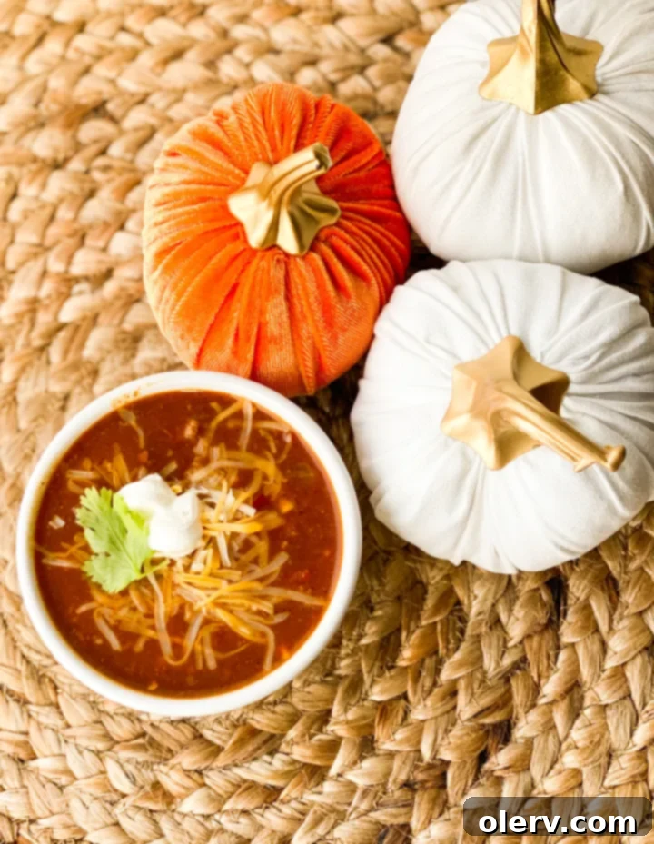Hearty Pumpkin Chili Recipe 2 A bowl of delicious pumpkin chili garnished with fresh herbs and a spoon, ready to be enjoyed.