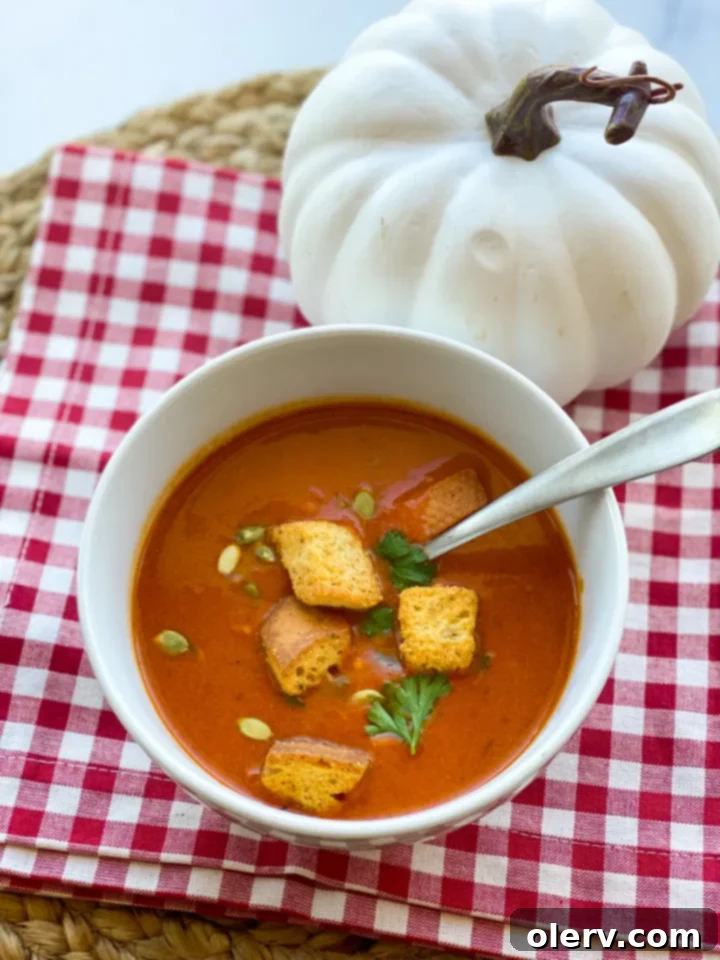 Velvet Roasted Red Pepper Pumpkin Soup 2 A vibrant bowl of roasted red pepper and pumpkin soup, garnished with fresh parsley, sitting on a rustic wooden table, perfect for autumn.