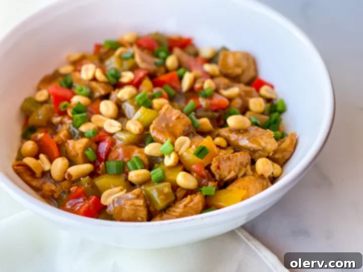 Speedy Instant Pot Kung Pao Chicken 3 A serving bowl of Instant Pot Kung Pao Chicken, featuring tender chicken, colorful bell peppers, and a rich, glossy sauce, with a serving spoon.