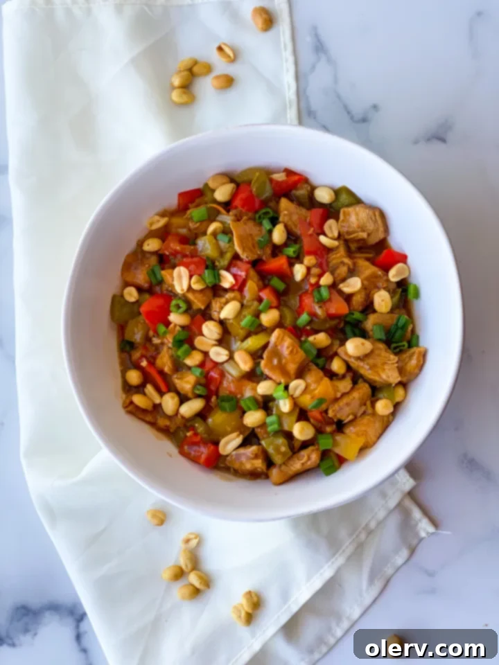 Speedy Instant Pot Kung Pao Chicken 4 Raw chicken pieces marinating in a bowl, positioned alongside a cutting board with freshly diced colorful bell peppers (red, yellow, green) and celery, all prepped and ready for the Instant Pot Kung Pao Chicken recipe.
