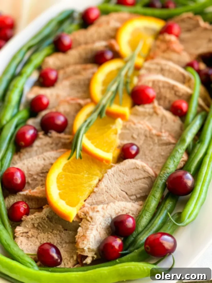 Instant Pot Cranberry Orange Glazed Pork Tenderloin 4 Close-up of cooked Instant Pot Cranberry Orange Pork Tenderloin slices with sauce and garnishes.
