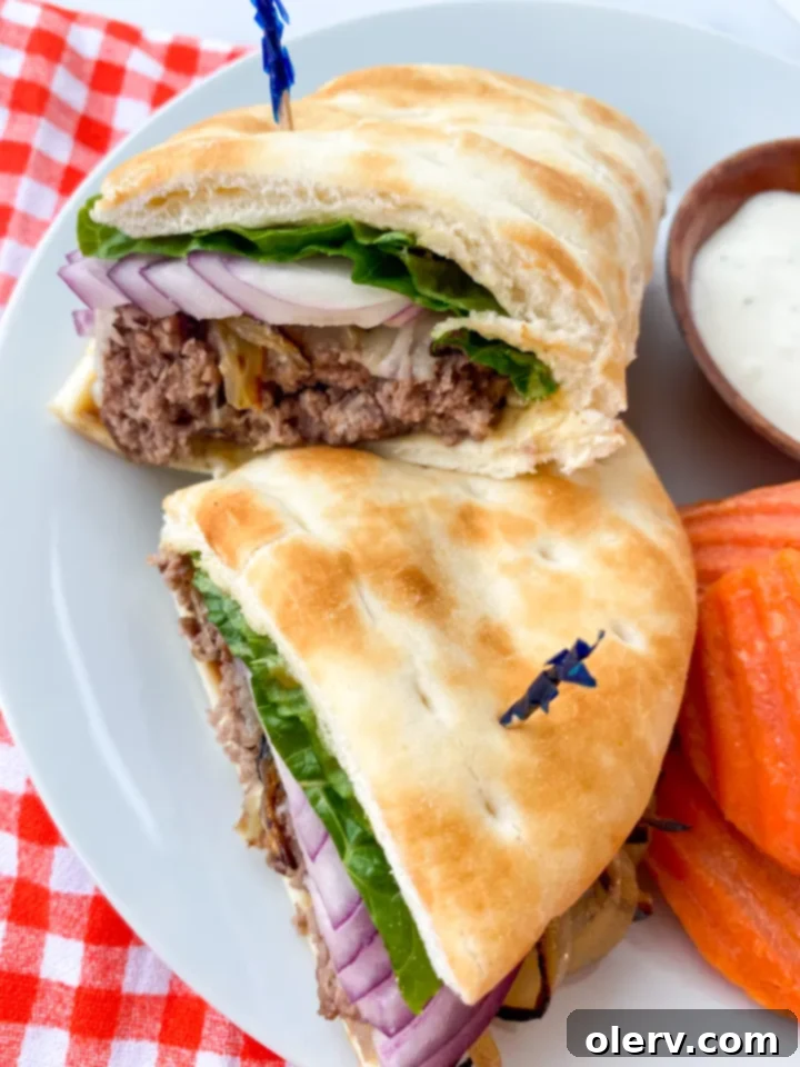 Perfect Air Fryer Burgers 7 Two air fryer hamburgers with melted cheese, nestled in pita bread with fresh toppings like lettuce and onions.