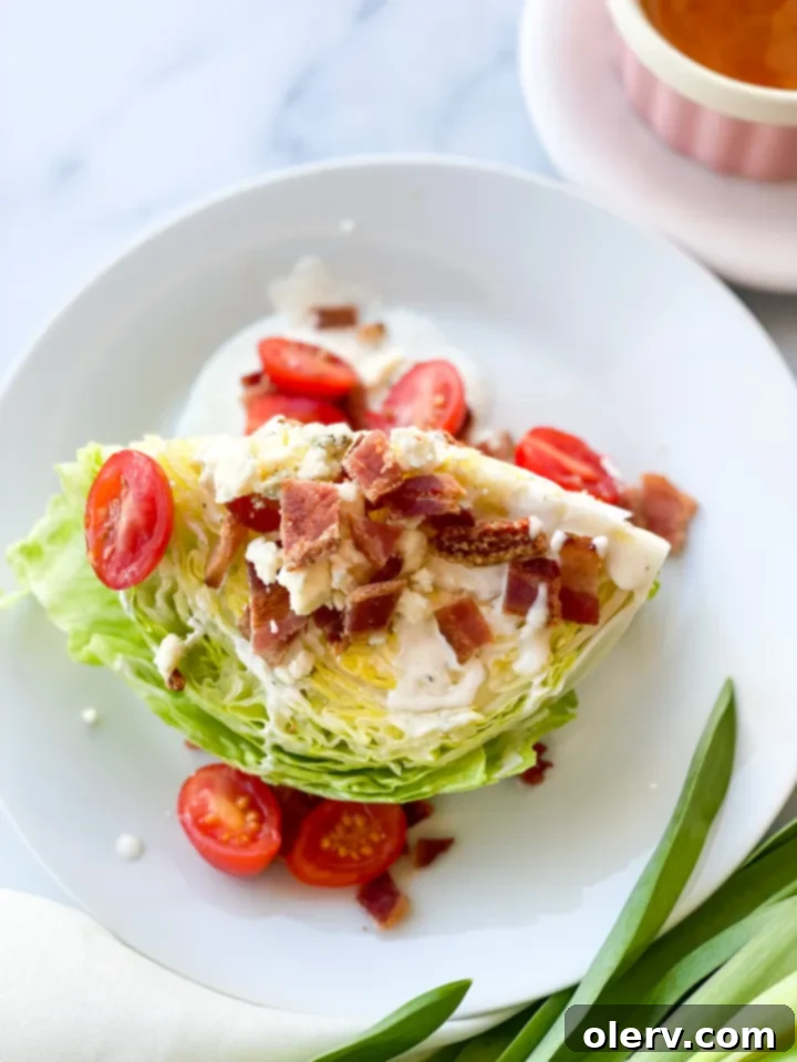 Crisp Wedge Salad 2 A freshly prepared Iceberg Wedge Salad on a chilled plate, garnished with crispy bacon, cherry tomatoes, and blue cheese dressing.
