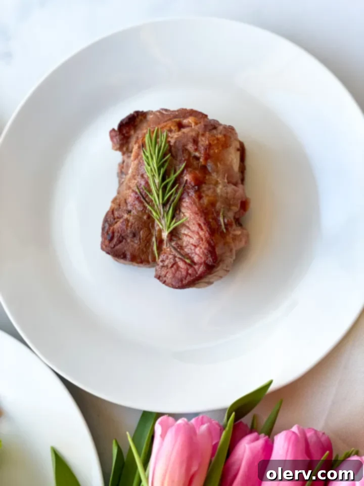 Garlic Butter Basted Steak 6 A perfectly cooked, butter-basted steak garnished with fresh rosemary and served on a platter.