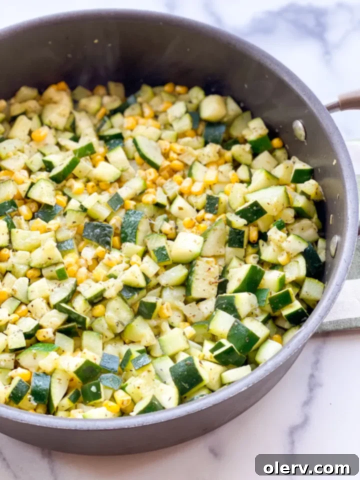 Savory Zucchini Side 2 Freshly cooked zucchini and corn side dish in a white bowl, garnished with lime and parmesan