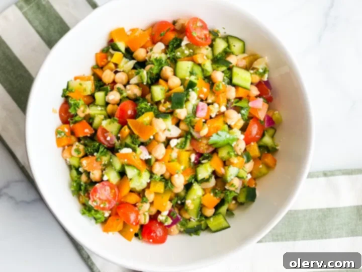 Vibrant Greek Chickpea Salad 3 Overhead shot of fresh ingredients for Greek Chickpea Salad, including chickpeas, chopped vegetables, and herbs.