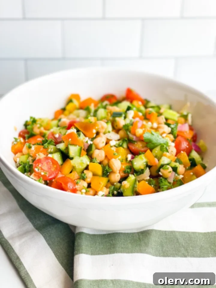 Vibrant Greek Chickpea Salad 5 Ingredients for Greek Chickpea Salad neatly arranged: chickpeas, tomatoes, cucumber, onion, bell pepper, and herbs.