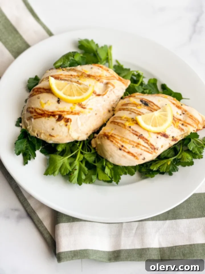 A hand gently rubs the lemon-yogurt marinade onto chicken breasts inside a resealable bag.