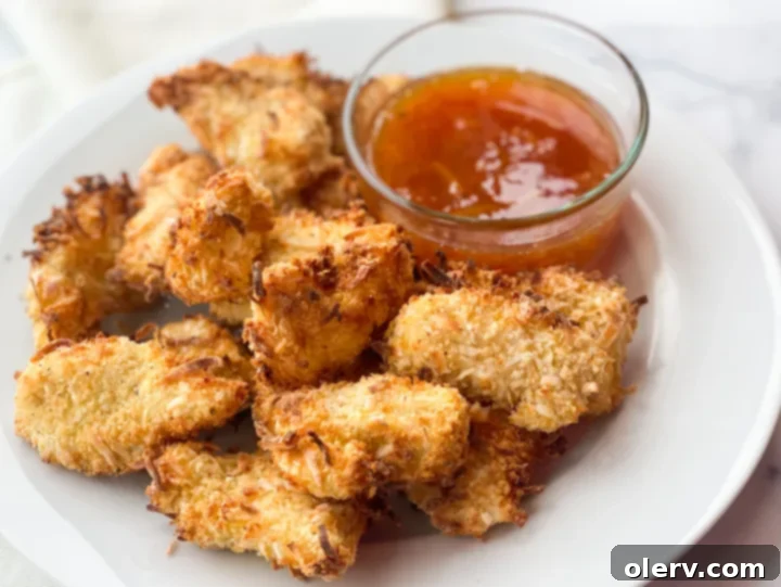 Golden Coconut-Crusted Chicken 5 Air fryer basket filled with freshly cooked crispy coconut chicken nuggets.