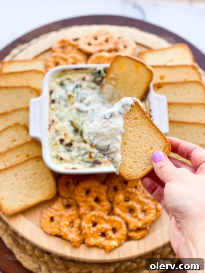 Effortless Oven Baked Spinach Artichoke Dip 4 Close-up of creamy spinach and artichoke dip being scooped