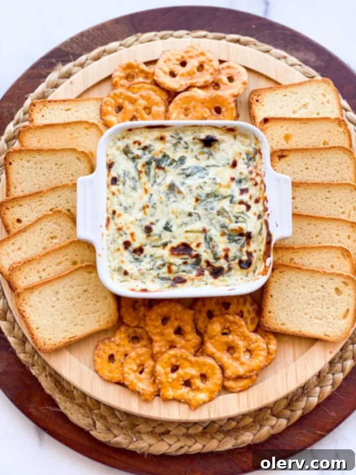Effortless Oven Baked Spinach Artichoke Dip 6 Variety of dippers surrounding a dish of spinach artichoke dip