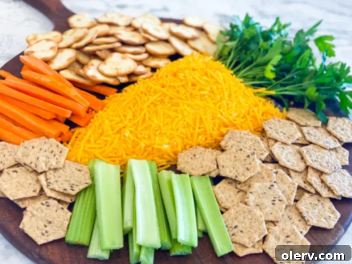 Close-up of the Easter Carrot Cheese Ball ingredients laid out on a kitchen counter: cream cheese blocks, jars of cheese spread, shredded cheddar, and fresh parsley.