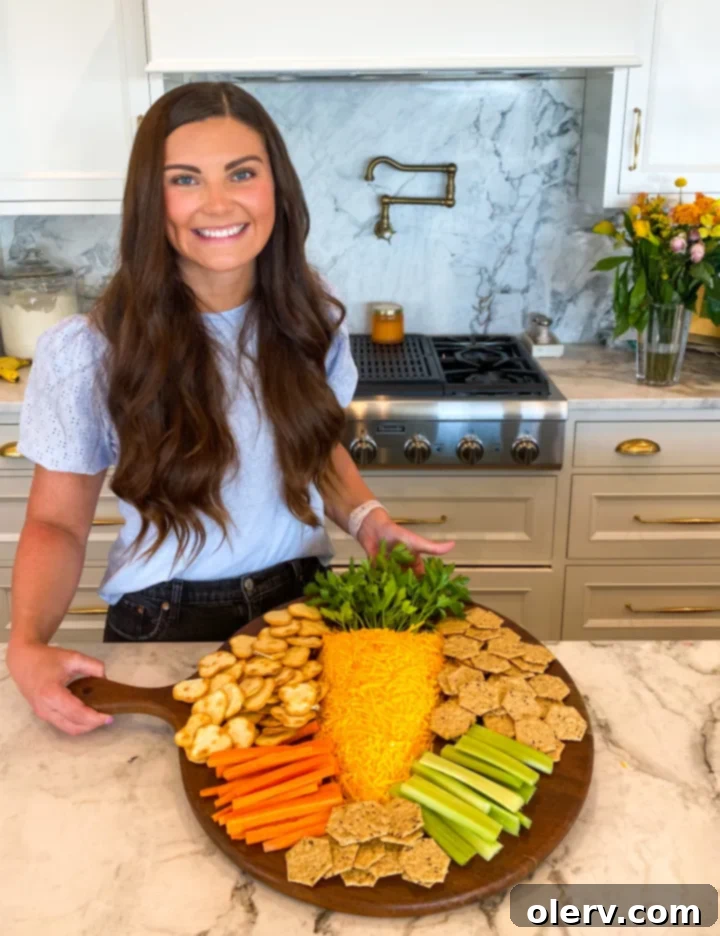 The Easter Carrot Cheese Ball fully formed and covered in shredded cheddar, with fresh parsley stems inserted at the top, ready for serving.