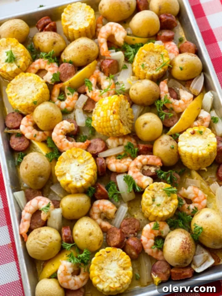 Sheet Pan Shrimp Feast 2 A vibrant sheet pan shrimp boil spread, featuring perfectly cooked shrimp, golden corn on the cob, tender red potatoes, and slices of smoked sausage, all seasoned with Old Bay and fresh herbs.