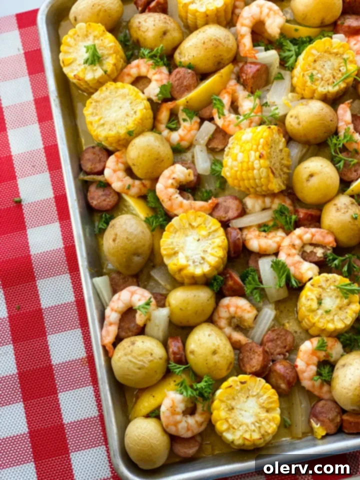 Sheet Pan Shrimp Feast 3 A close-up shot of raw shrimp, corn, and sausage artfully arranged on a sheet pan, ready to be seasoned and roasted for a simple shrimp boil.