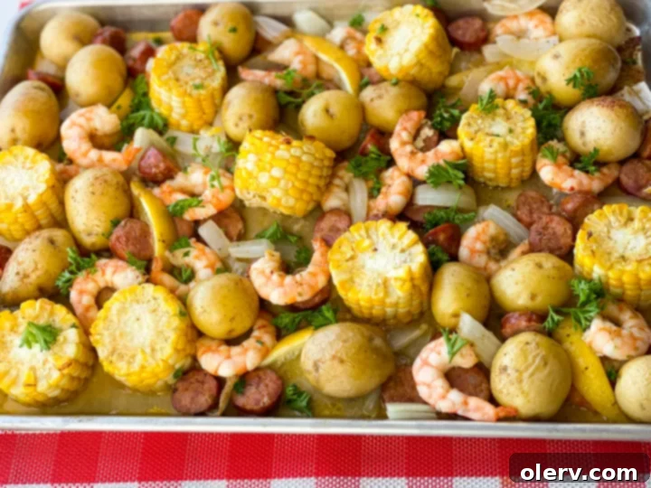 Sheet Pan Shrimp Feast 5 An overhead view of a rustic wooden table covered with newspaper, piled high with a classic shrimp boil. Cooked shrimp, corn, potatoes, and sausage are ready to be enjoyed by hand.