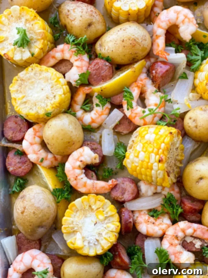Sheet Pan Shrimp Feast 6 A close-up of perfectly roasted shrimp, corn, and sausage on a sheet pan, drizzled with a rich garlic butter sauce and garnished with fresh parsley.