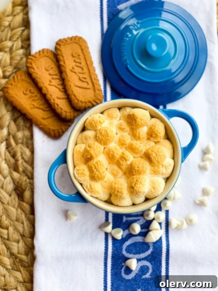 Caramelized Biscoff Smore Cups 2 Delicious Biscoff S'more Cups with melted white chocolate and golden-brown marshmallows in a mini dutch oven, ready to be enjoyed.