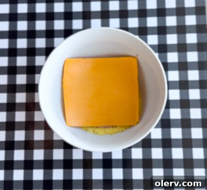 Instant Breakfast Sandwich 9 Step 5: Adding a slice of cheddar cheese on top of the ham and egg