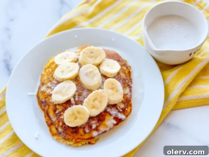 Liquid Coconut Gold 5 Pancakes topped generously with homemade coconut syrup, fresh banana slices, and crushed macadamia nuts