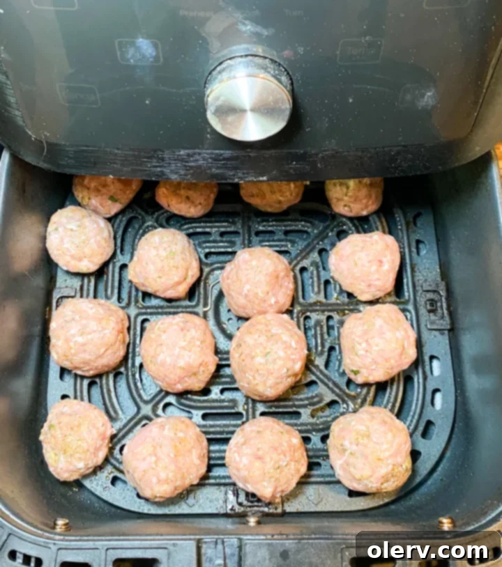 Perfect Air Fryer Turkey Meatballs 5 Air Fryer Turkey Meatballs cooking in the air fryer basket, turning golden brown.
