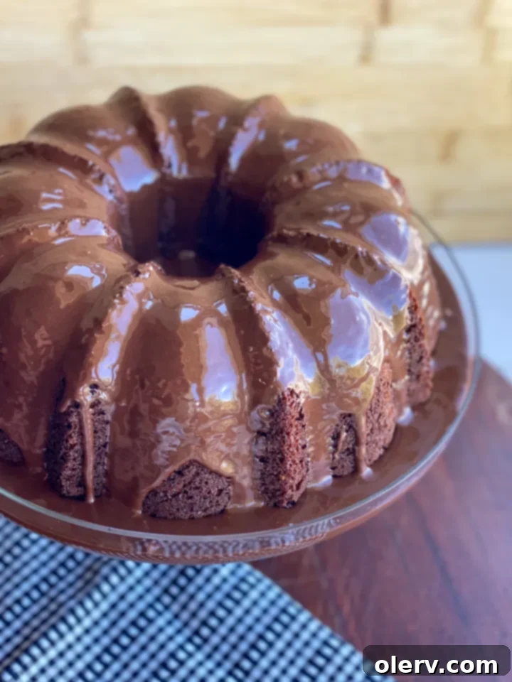 Decadent Chocolate Bundt 3 A slice of moist chocolate bundt cake on a plate, drizzled with chocolate glaze.