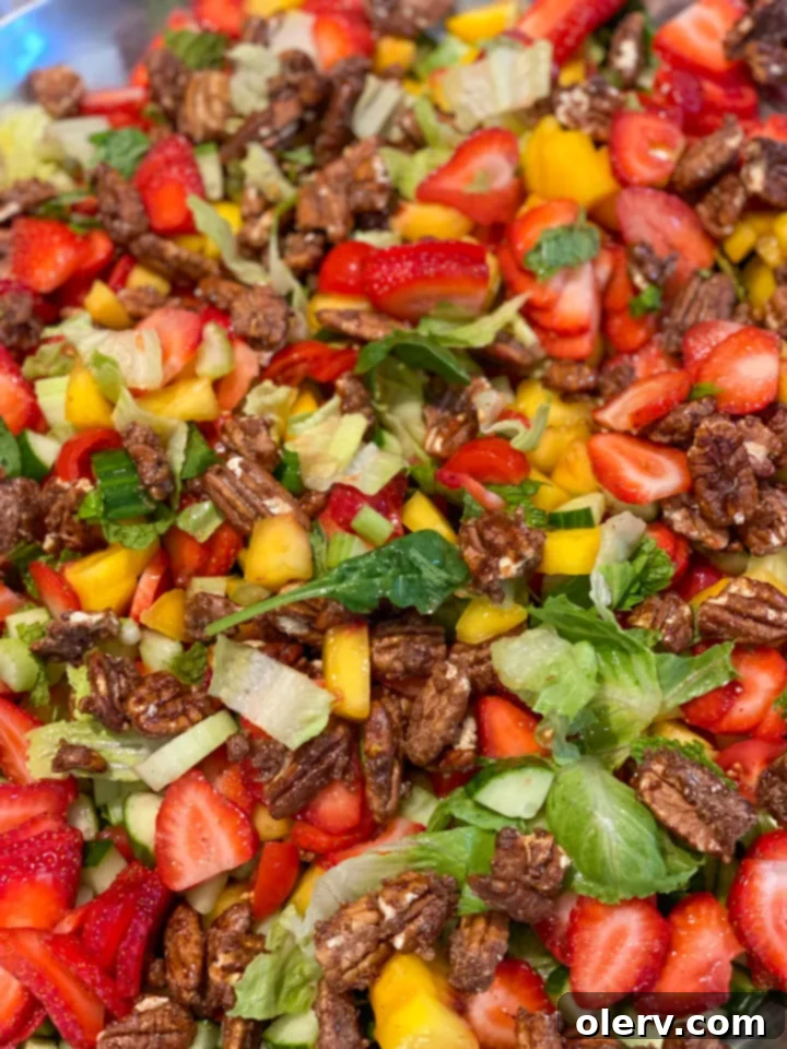 Vibrant Spinach Strawberry Salad 4 A bowl filled with freshly prepped ingredients for the salad, including diced peaches covered in orange juice to prevent browning, sliced strawberries, and chopped vegetables, ready for assembly.