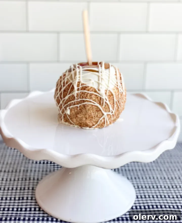 Easy Homemade Caramel Apples 6 A gourmet caramel apple being drizzled with white chocolate