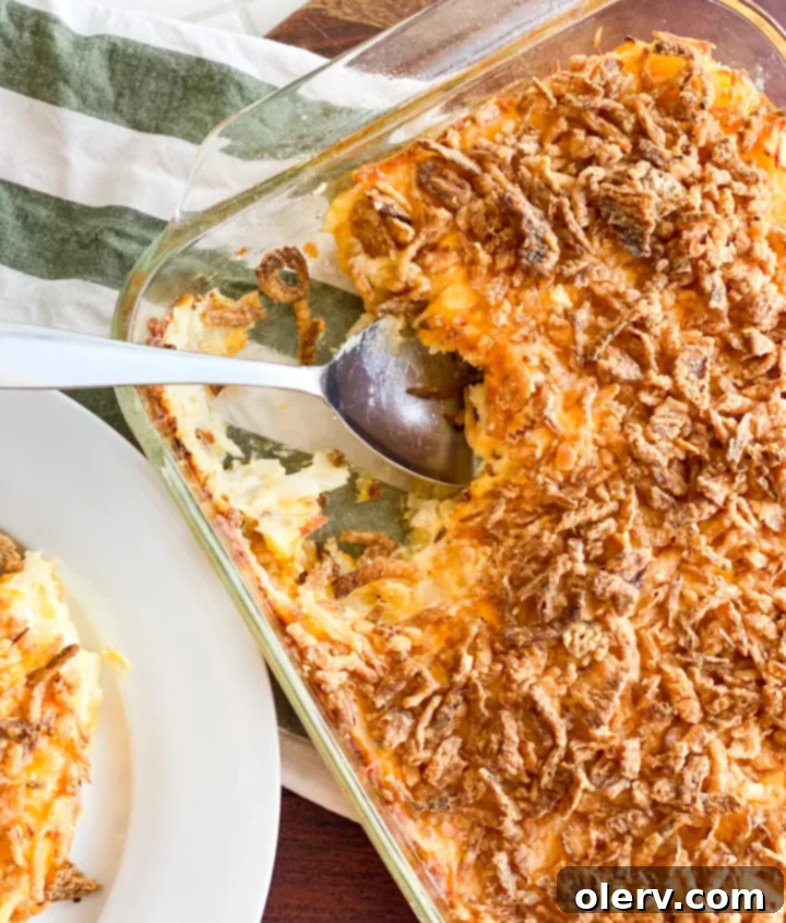 Hearty Cheesy Potato Bake 3 A baking dish filled with Funeral Potatoes, topped with golden-brown crispy onions and melted cheese, ready to be served.