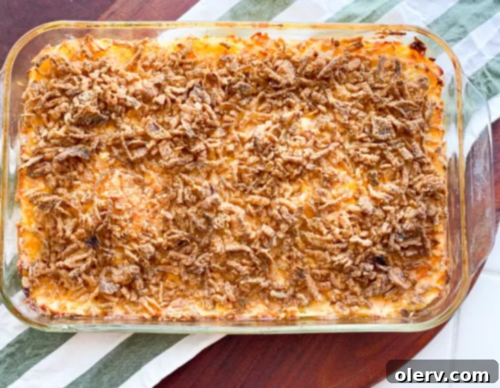 Hearty Cheesy Potato Bake 5 A large mixing bowl containing the Funeral Potato mixture, with hash browns, cheese, sour cream, and cooked onions, ready to be transferred to a baking dish.