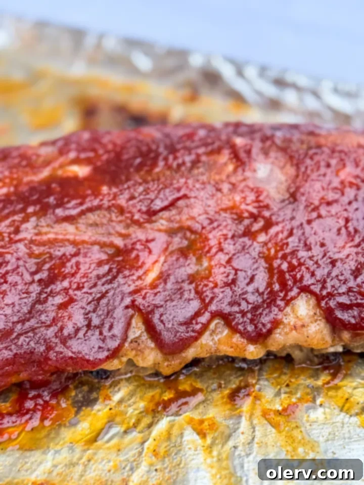 Fall-Off-The-Bone Oven Ribs 3 A close-up of tender BBQ Ribs in the oven, glistening with sauce