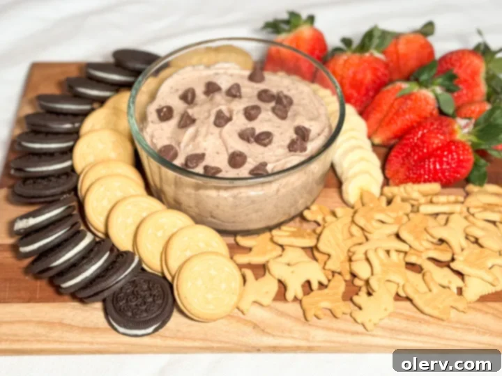 Irresistible Chocolate Chip Dip 5 Assortment of colorful dippers including fresh strawberries, banana slices, animal crackers, and various cookies neatly arranged around a bowl of chocolate chip dip, creating an inviting display.