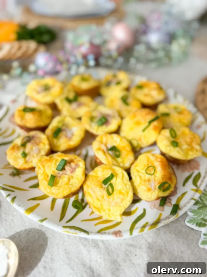 Petite Quiche Bites 2 A close-up shot of a golden-brown mini quiche, garnished with fresh green onions, sitting on a wooden surface.