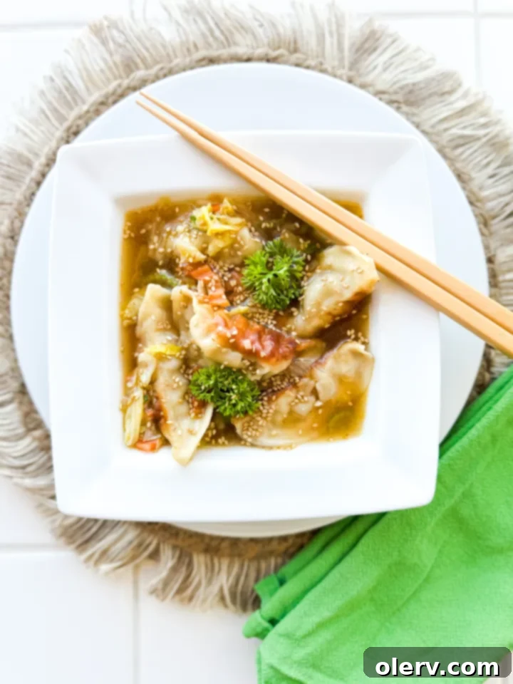A steaming bowl of Potsticker Soup garnished with sesame seeds and green onions.