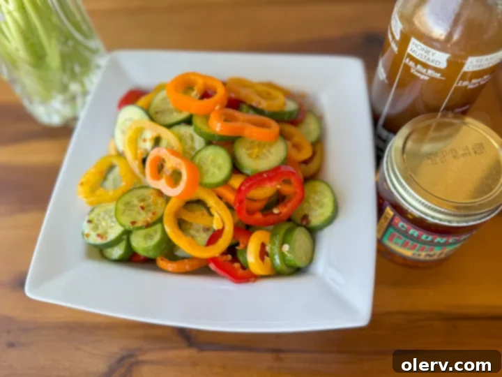 Vibrant Cucumber Pepper Mix 4 A bowl of sliced mini cucumbers and bell peppers on a white surface.