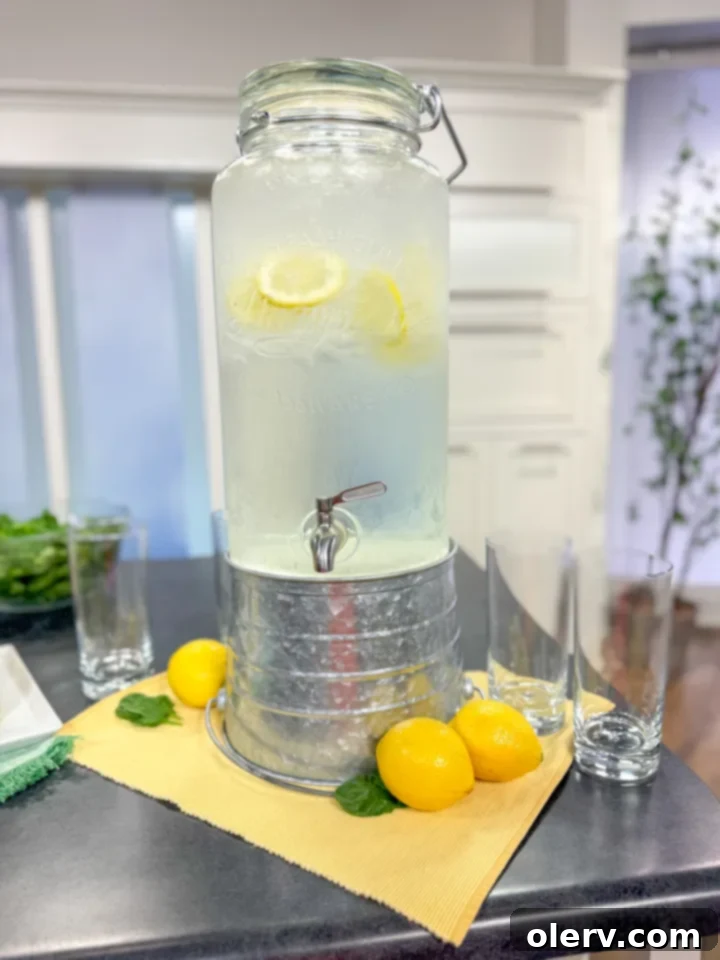 Refreshing Homemade Lemon Water 2 Delicious lemon water in a dispenser with vibrant lemon slices, ready to be served at an event.