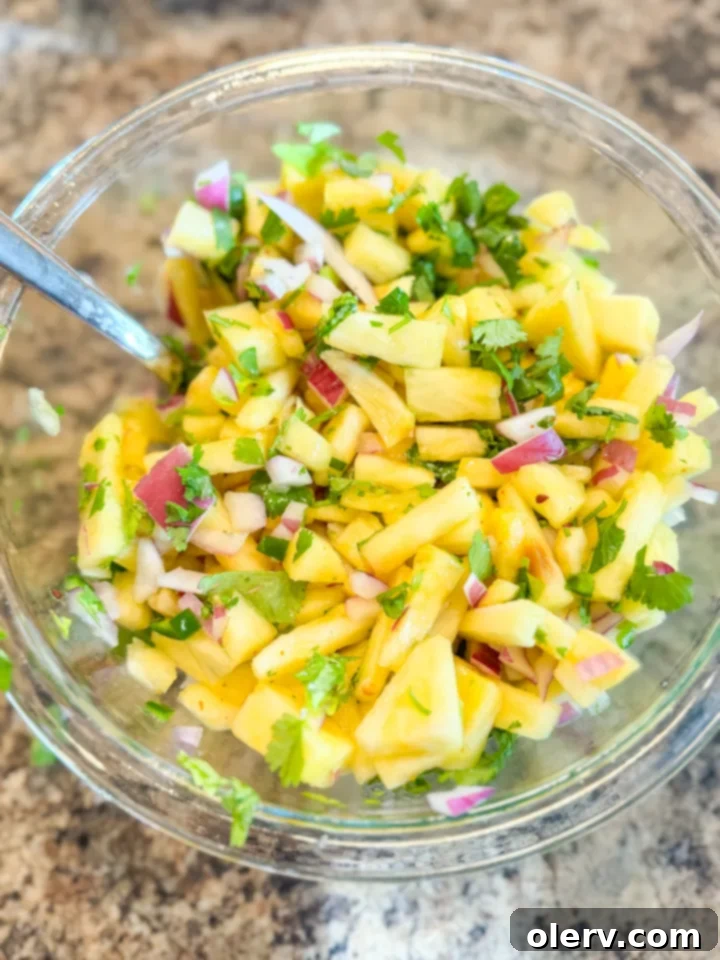 Crispy Air Fryer Shrimp Tacos 3 Close-up of a single air fryer shrimp taco, garnished with fresh pineapple salsa, avocado, and cilantro