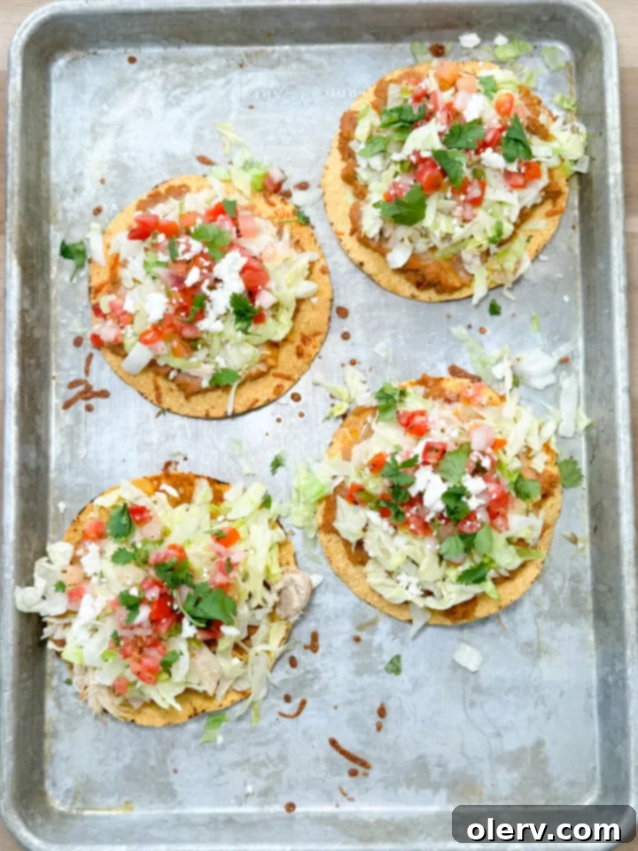 Crispy Chicken Tostadas 3 Two baked chicken tostadas on a serving plate, showcasing the layers of ingredients.