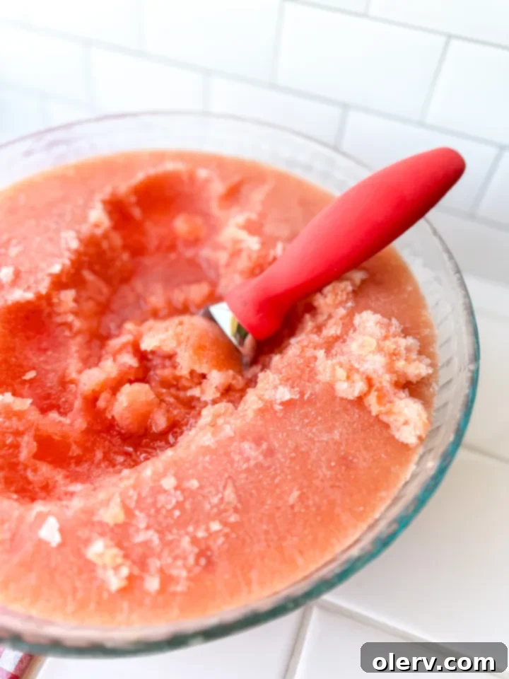 A glass of refreshing Frozen Summer Slush being held, showcasing the vibrant drink
