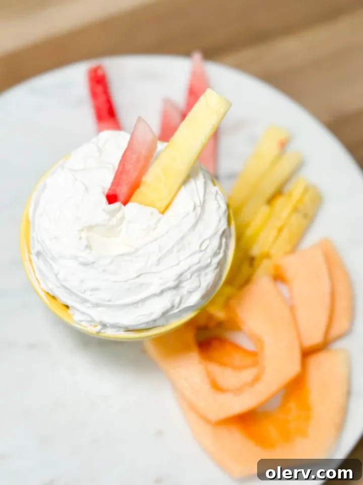 Quick Creamy Fruit Dip 2 A vibrant platter of fresh fruits like strawberries, blueberries, and apple slices, perfectly arranged around a bowl of fluffy, creamy fruit dip, ready for dipping.